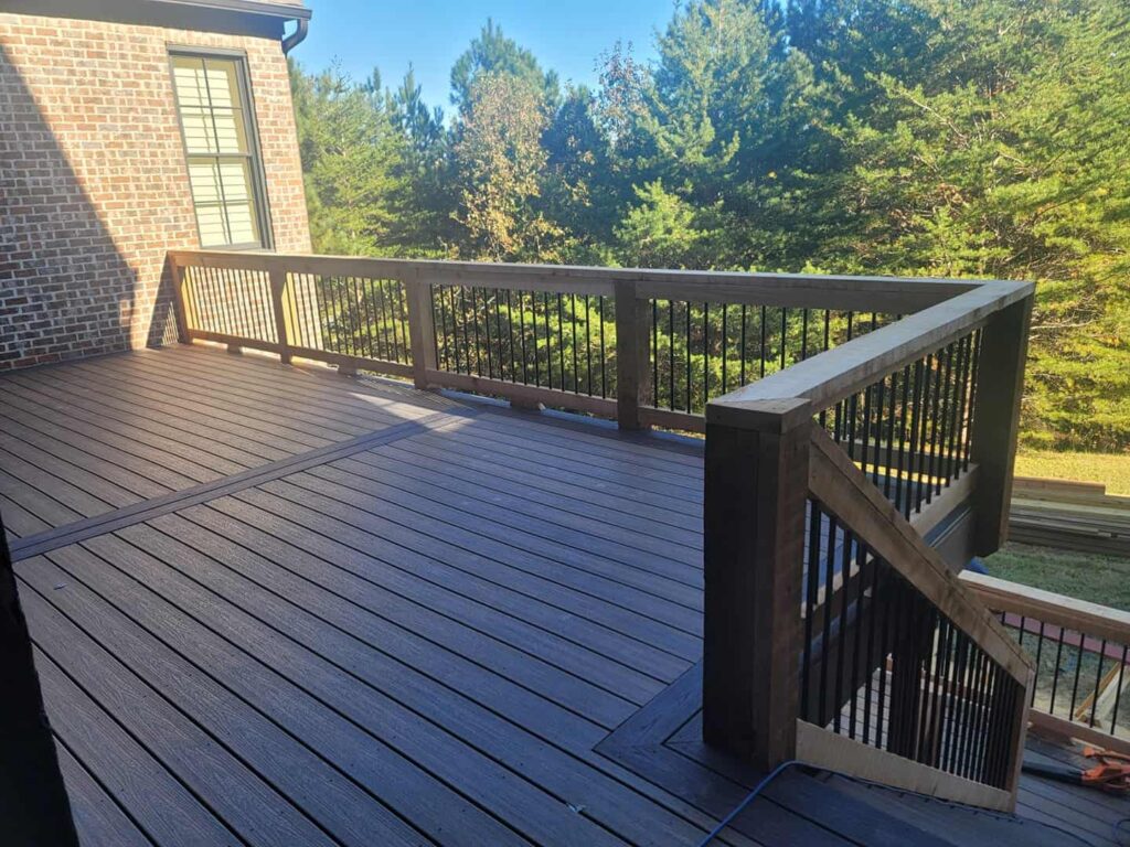 Composite deck with stairs and dark railing overlooking a wooded yard by Elite Decks, deck builder serving Irondale, AL