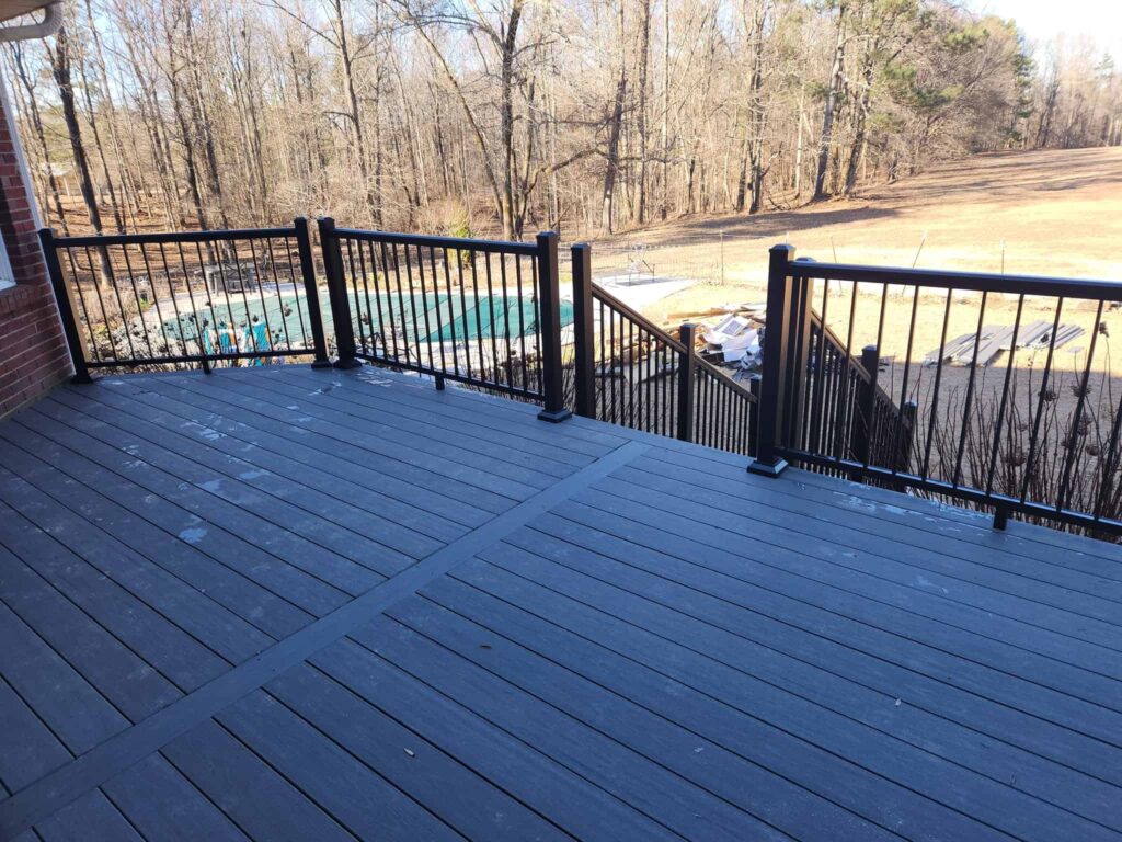 Custom deck with black railing overlooking a wooded yard by Elite Decks, deck builder serving Leeds, AL