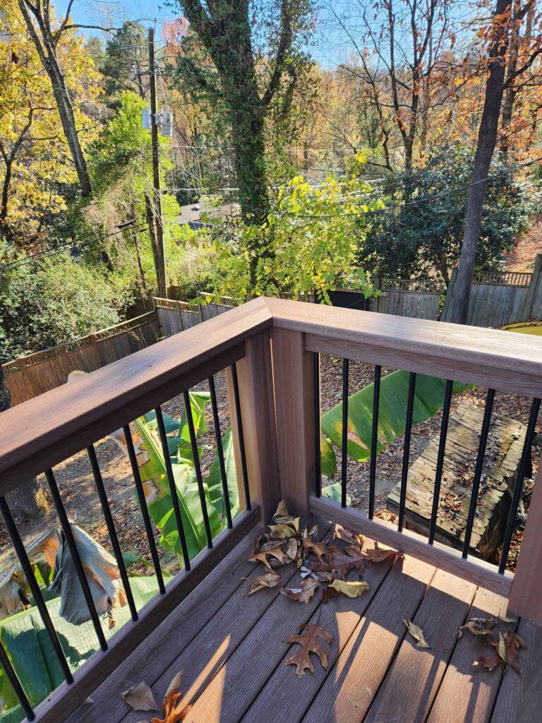 Custom deck with wood railing overlooking a wooded backyard by Elite Decks, deck builder serving Warrior, AL